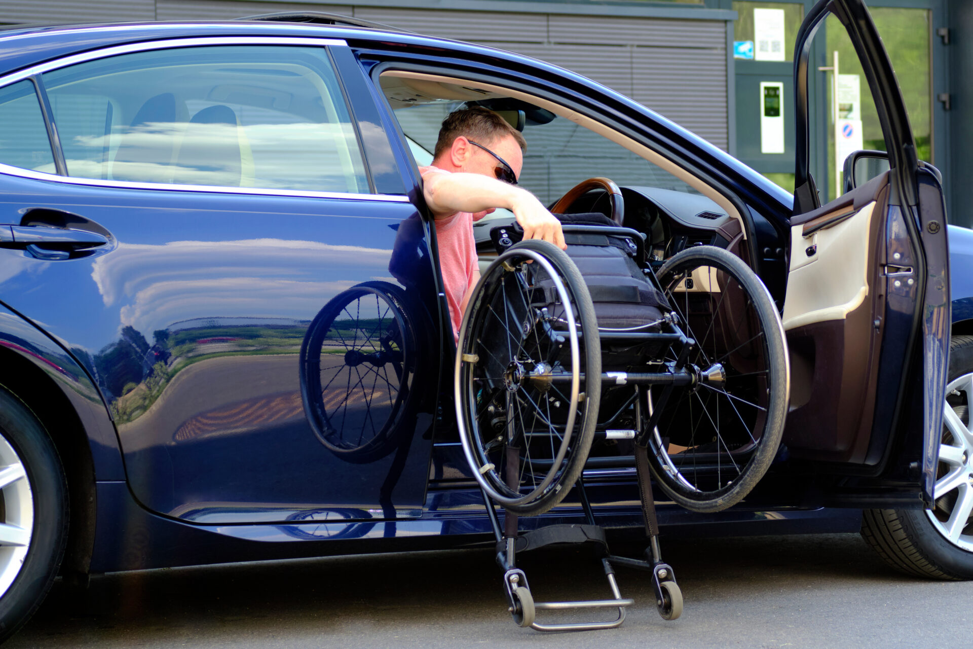 Conducteur à mobilité réduite sortant son fauteuil roulant de son véhicule